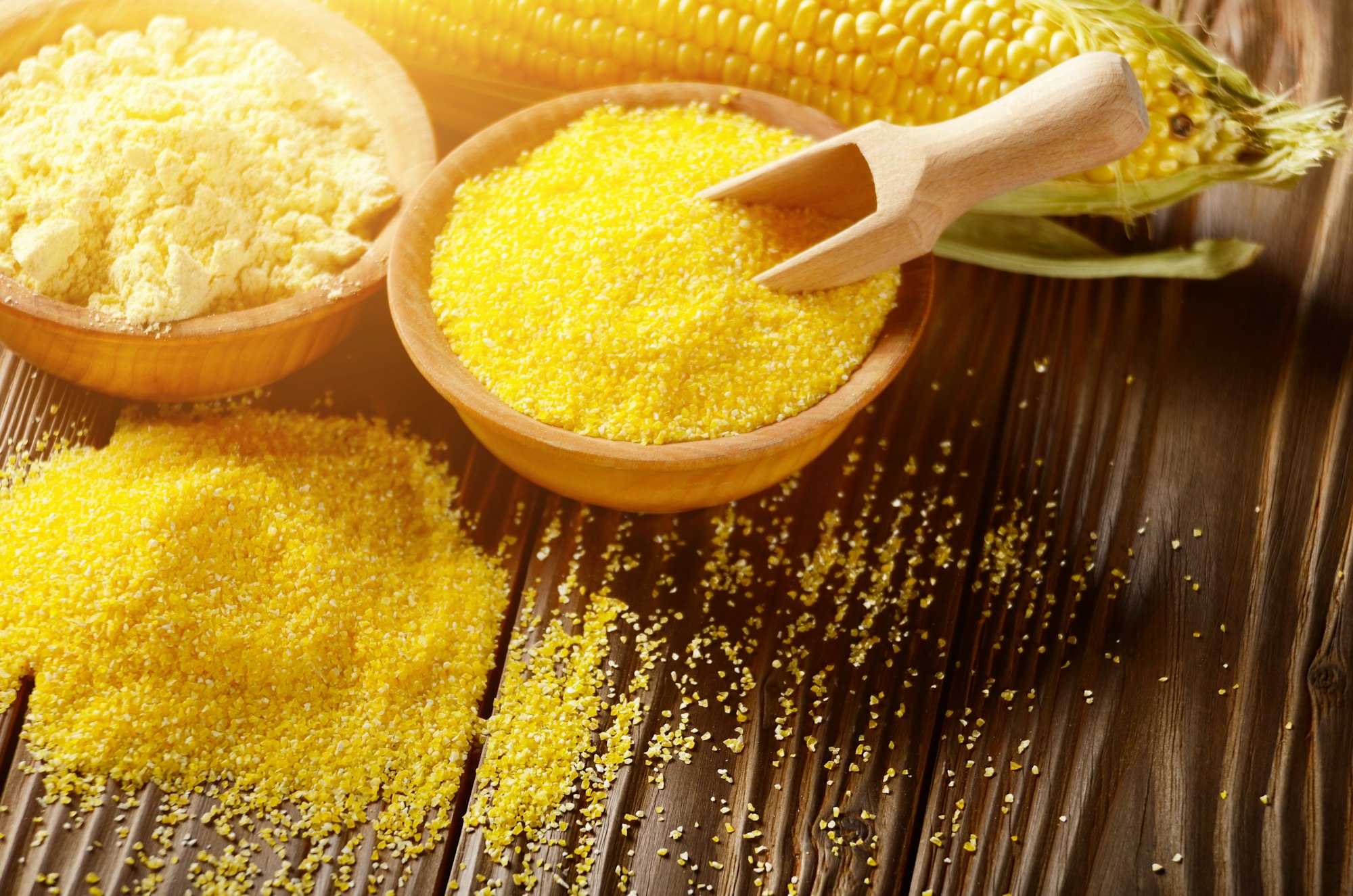 Bowl of corn grits corncob and corn flour on kitchen table