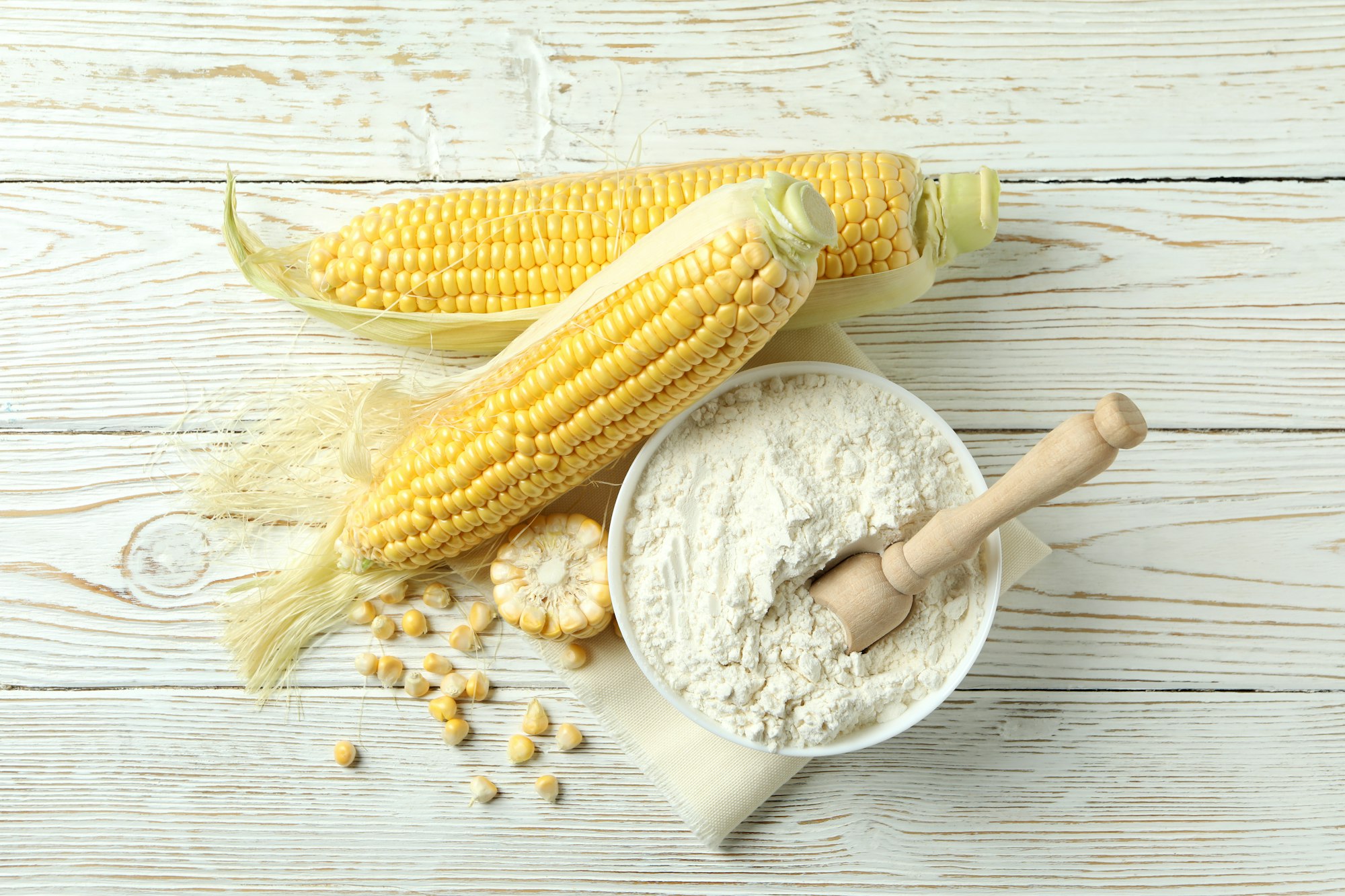 Raw corn and flour on white wooden table